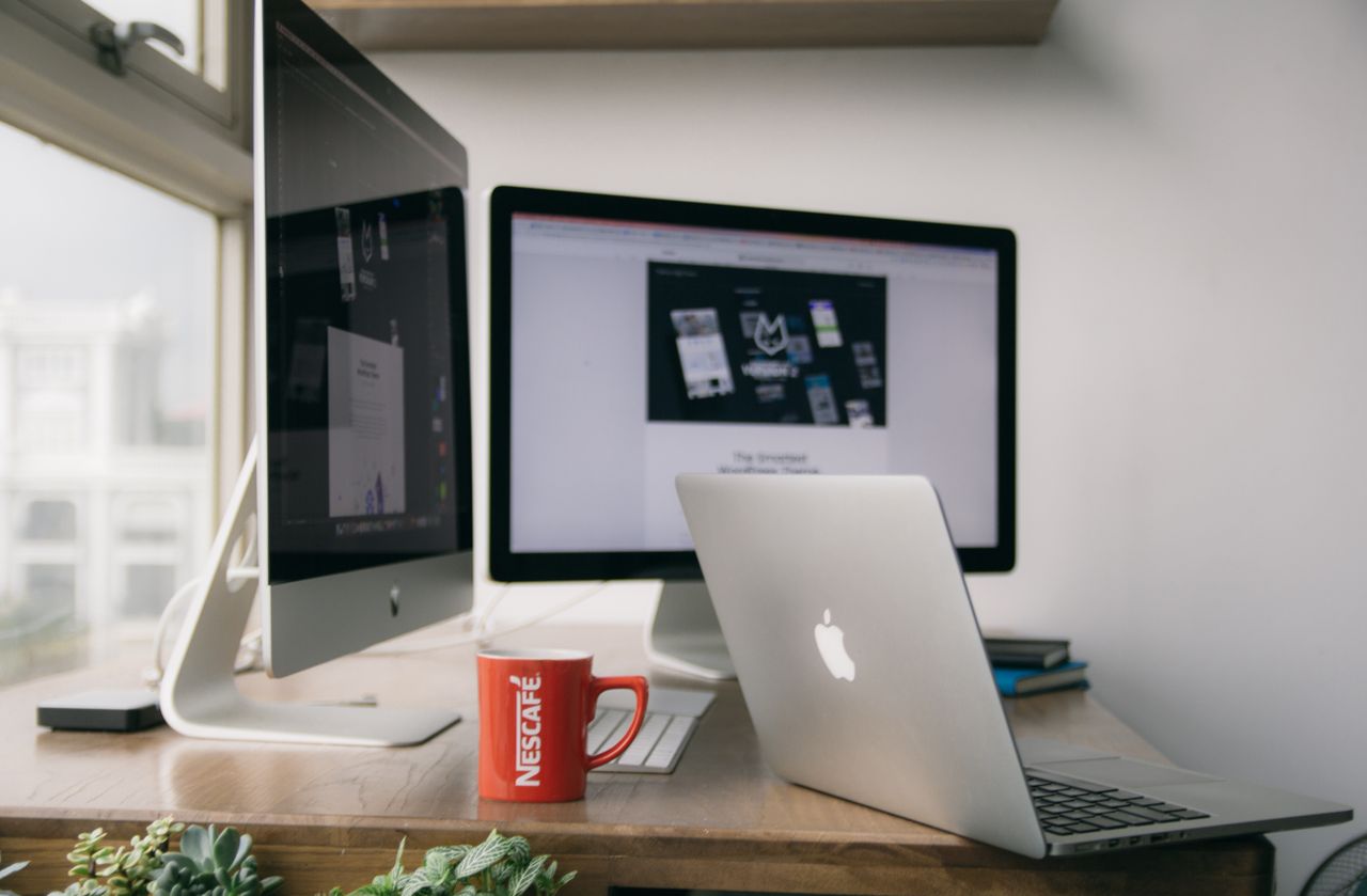 home-hero A bright modern office setup with computers and a mug on a desk.